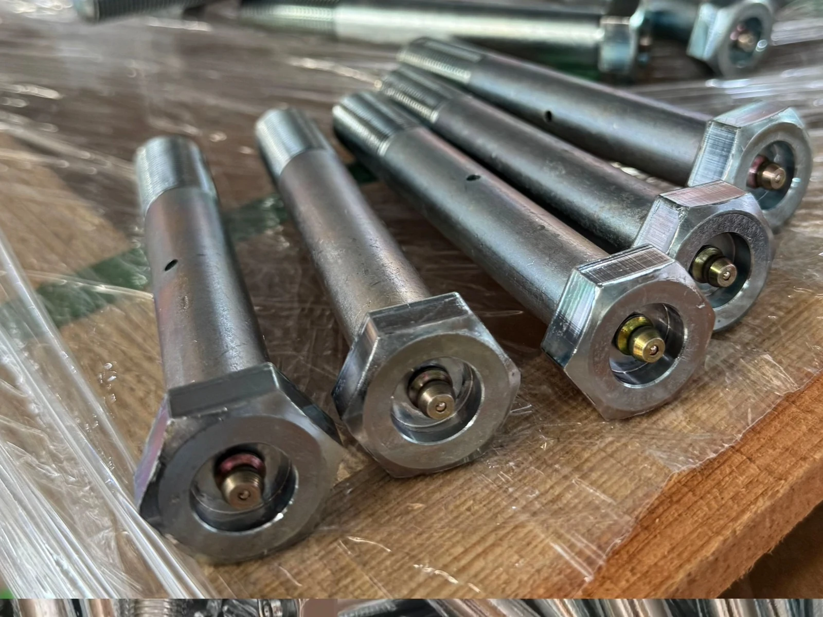 Custom hex-head bolts with integrated grease fittings arranged for inspection on a workbench.